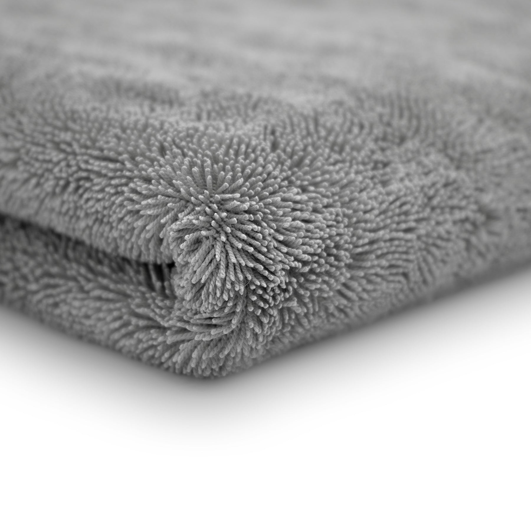 Dettaglio ravvicinato di un panno in microfibra grigio ultra assorbente, con una trama densa e soffice, ideale per asciugare l'auto senza lasciare tracce.