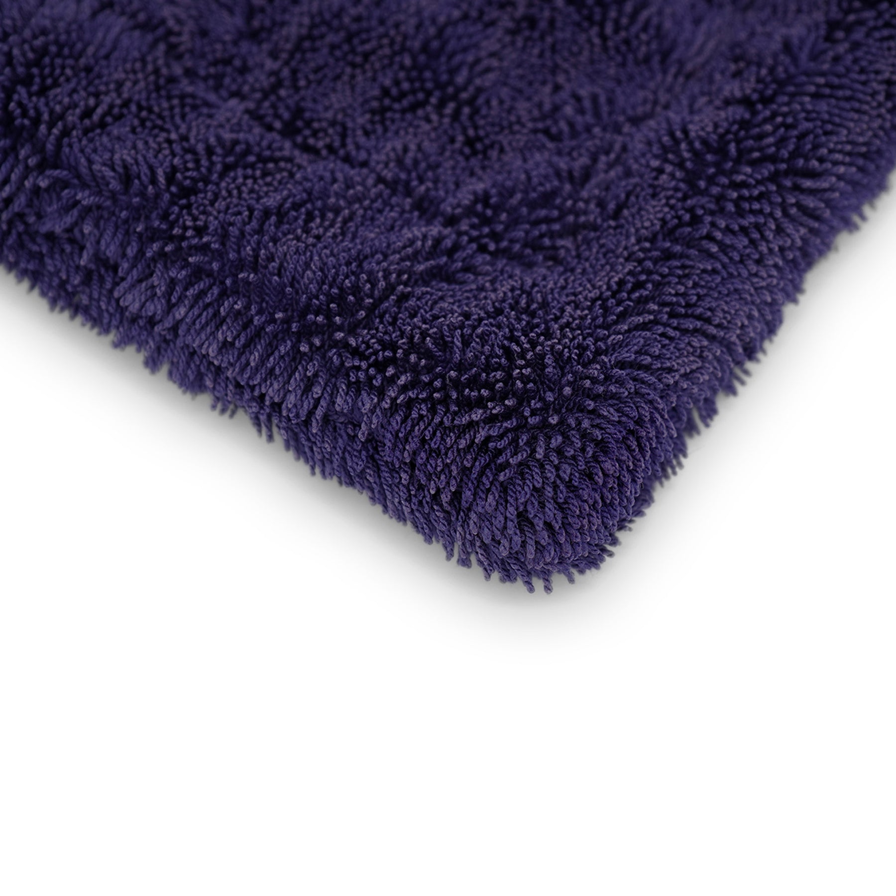 Dettaglio angolare di un panno in microfibra blu scuro, assorbente, ideale per un'asciugatura delicata e priva di aloni delle superfici auto.